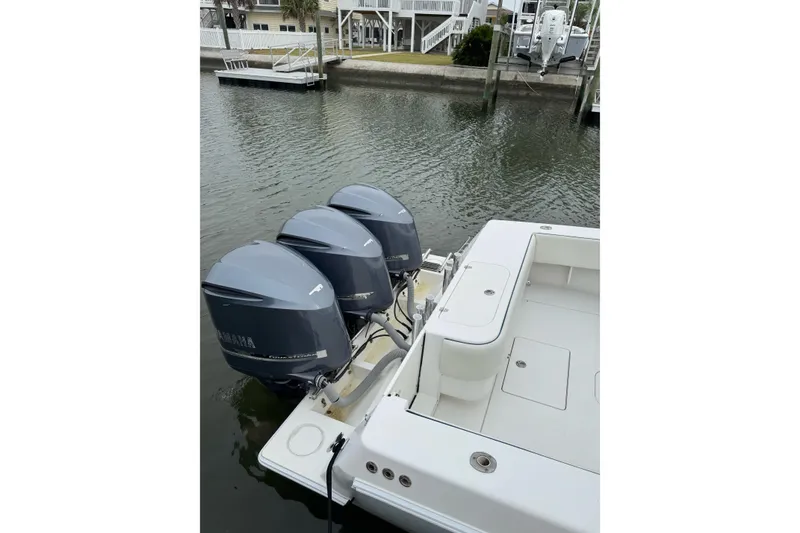 Slide: The Image of 2008 Contender 36 Fisharound with triple Yamaha outboard engines docked by the water. - 6