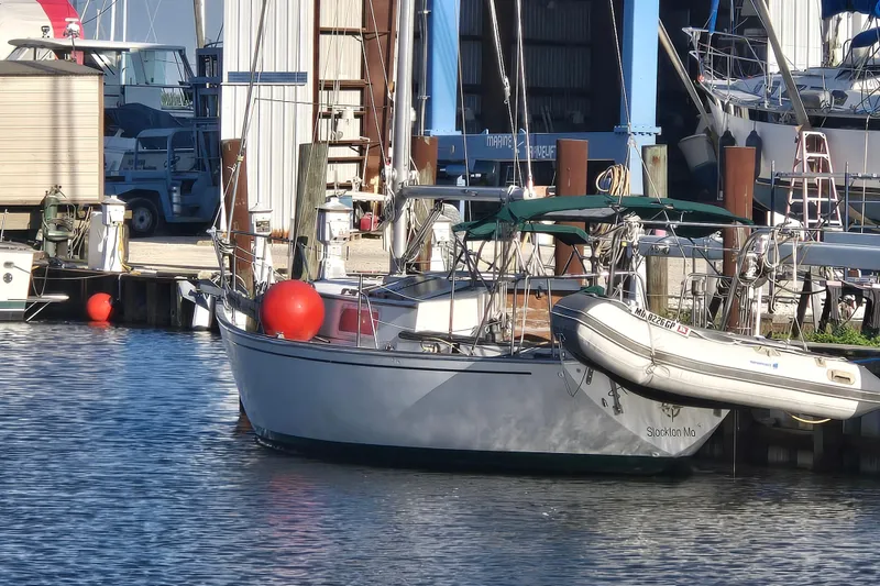 Slide: The Image of 1981 Morgan 321 sailboat docked at marina with inflatable dinghy attached. - 1