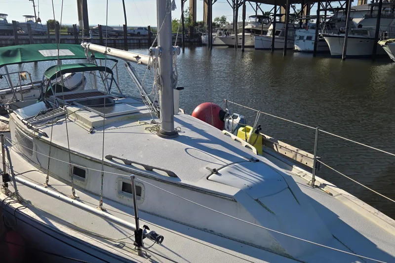 Slide: The Image of 1981 Morgan 321 sailboat docked in a marina, featuring a green canopy and calm waters. - 2