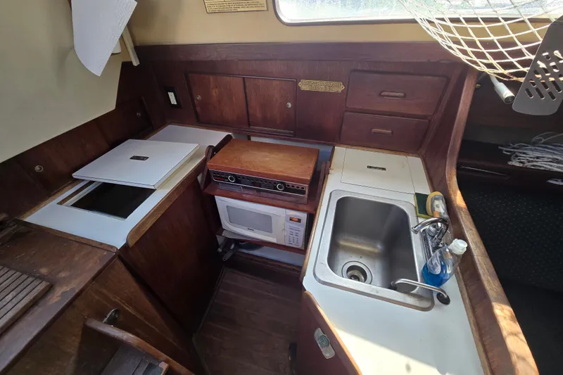 Slide: The Image of 1981 Morgan 321 yacht kitchen with sink, stove, microwave, and wooden cabinetry. - 8