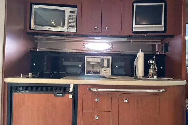 Slide: The Image of 2004 Chaparral Signature 350 yacht kitchen with microwave, TV, and wooden cabinetry. - 9