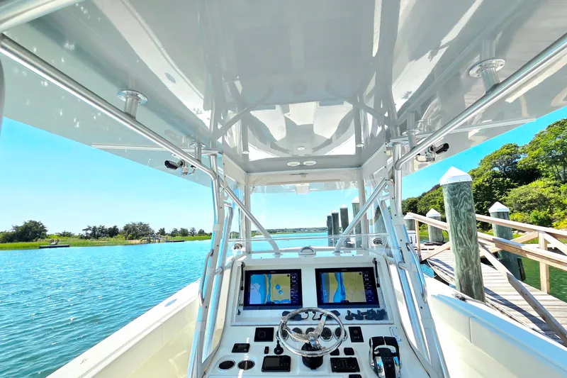 Slide: The Image of 2016 SeaVee 390Z boat cockpit with dual navigation screens, docked by a scenic waterway. - 5