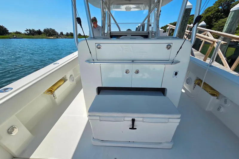 Slide: The Image of 2016 SeaVee 390Z boat interior with storage and seating, docked by a scenic waterway. - 8