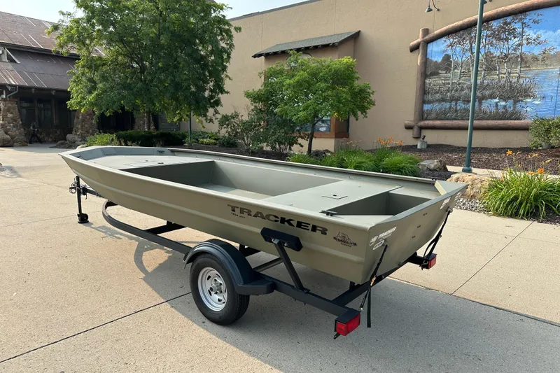 Slide: The Image of 2026 Tracker Grizzly 1754 Utility boat on trailer, parked outdoors near a building. - 2