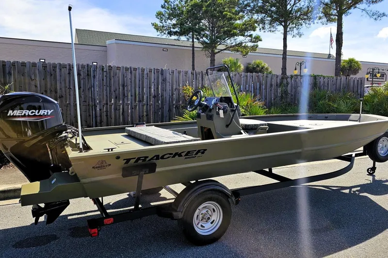 Slide: The Image of 2026 Tracker Grizzly 1860 CC boat with Mercury engine on trailer, parked outdoors. - 2