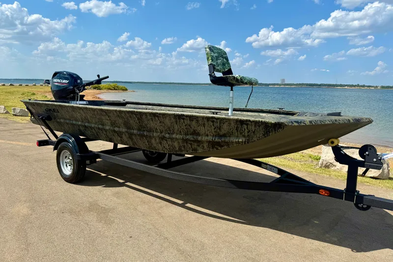 The Image of 2026 Tracker Grizzly 1654 T Sportsman boat on trailer by a scenic lake. - 0