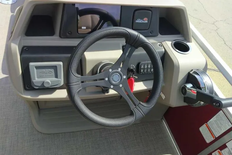 Slide: The Image of 2025 Sun Tracker Party Barge 24 DLX steering console with controls and cup holder. - 3