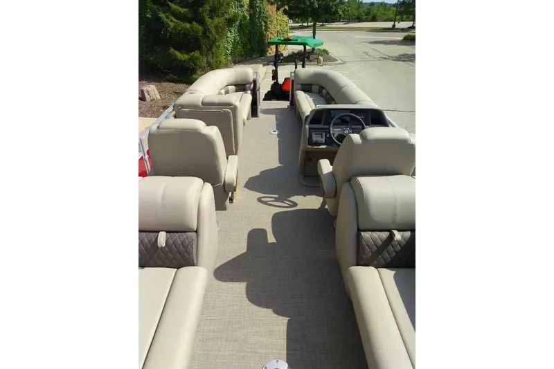 Slide: The Image of 2025 Sun Tracker Party Barge 24 DLX interior with beige seating and steering console. - 4