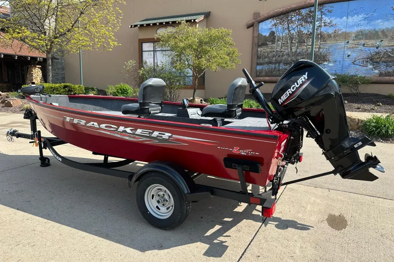 Slide: The Image of 2025 Tracker Super Guide V-16 T boat with Mercury engine, parked outdoors. - 2