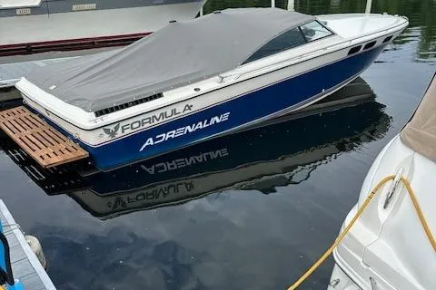 Slide: The Image of 1984 Formula 272 Adrenaline speedboat docked, covered, and reflecting on calm water. - 12