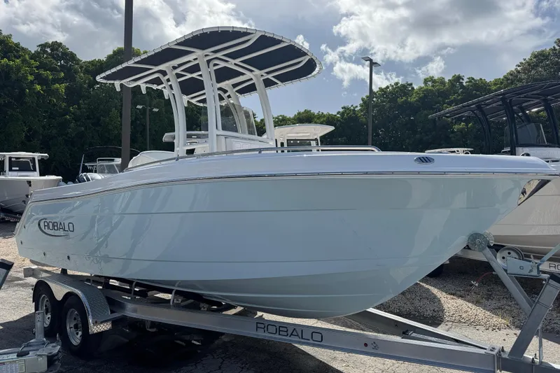 The Image of 2025 Robalo R222 Explorer boat on trailer, parked outdoors under cloudy sky. - 0