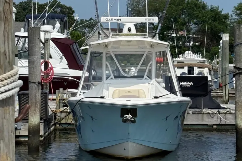 Slide: The Image of 2019 Cobia 277 Center Console boat docked, featuring a vibrant fish mural. - 1