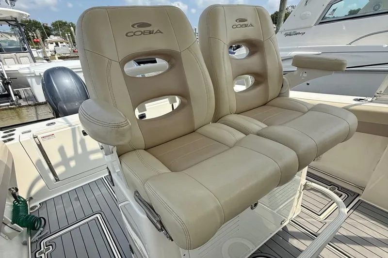 Slide: The Image of 2019 Cobia 277 Center Console boat with beige cushioned seating and armrests. - 14