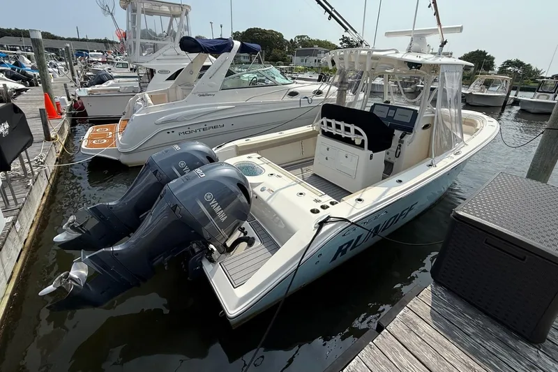 Slide: The Image of 2019 Cobia 277 Center Console boat docked with twin Yamaha engines. - 2