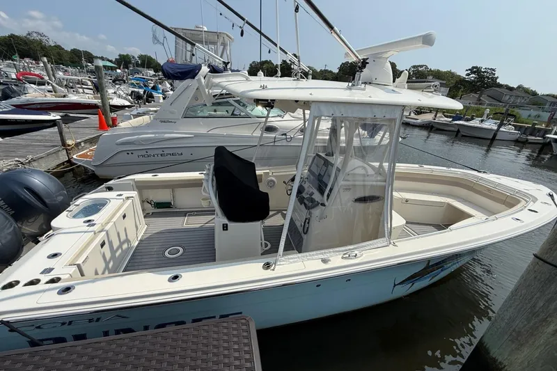Slide: The Image of 2019 Cobia 277 Center Console boat docked at a marina with other vessels. - 5