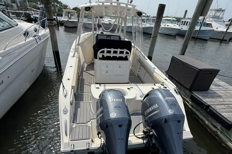 Slide: The Image of 2019 Cobia 277 Center Console boat docked, featuring twin Yamaha 200 engines. - 7