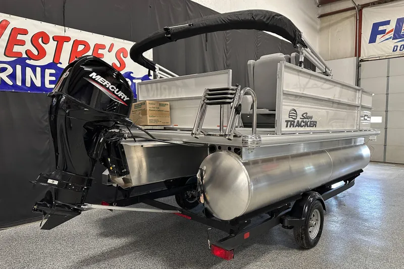 Slide: The Image of 2026 Sun Tracker Party Barge 16 DLX pontoon boat with Mercury engine in showroom. - 3
