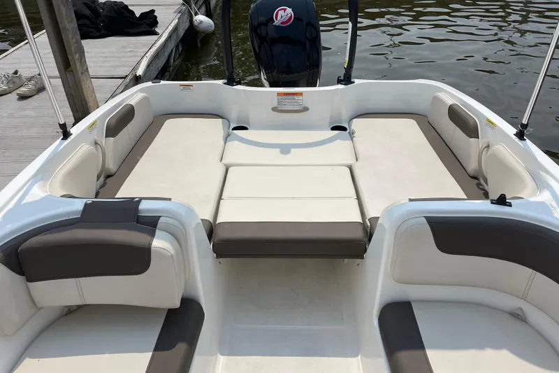 Slide: The Image of 2020 Bayliner Element boat interior with cushioned seating, docked by the water. - 13