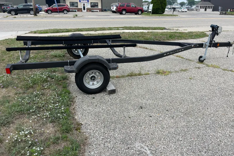Slide: The Image of 2020 Bayliner Element boat trailer parked on a gravel surface near a road. - 24
