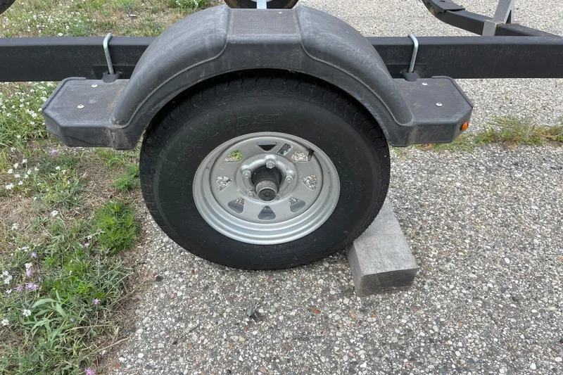 Slide: The Image of Trailer wheel of a 2020 Bayliner Element, secured with a block on gravel. - 25