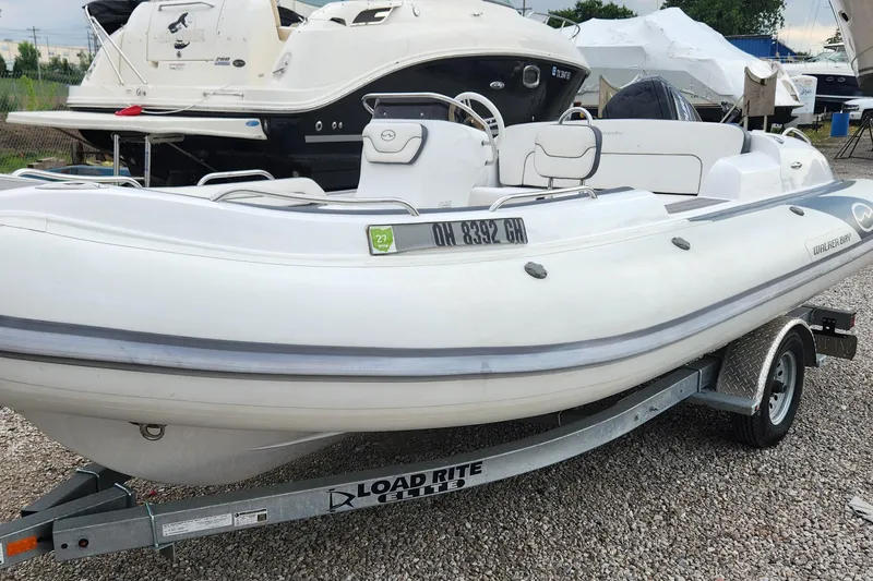 Slide: The Image of 2022 Walker Bay Generation 525 DLX boat on Load Rite trailer, parked on gravel. - 2