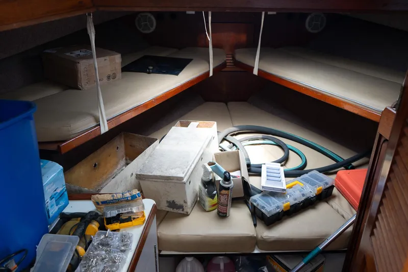 Slide: The Image of 1978 Bertram 35 Flybridge Sportfish cabin with tools and supplies scattered on cushions. - 14