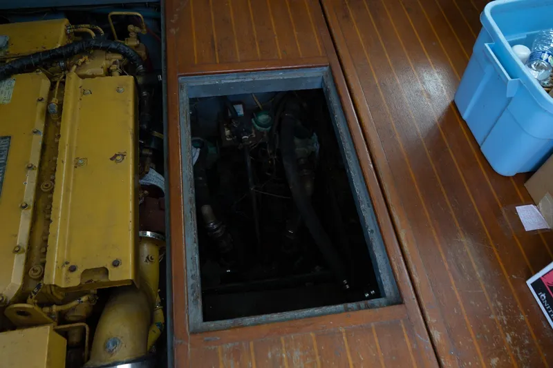 Slide: The Image of 1978 Bertram 35 Flybridge Sportfish engine compartment with yellow engine and wooden flooring. - 24
