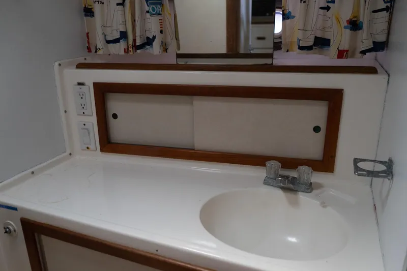 Slide: The Image of 1978 Bertram 35 Flybridge Sportfish bathroom sink with mirror and nautical curtains. - 35