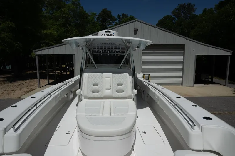 Slide: The Image of 2023 Contender 44 ST boat with white seating, docked near a metal building. - 6