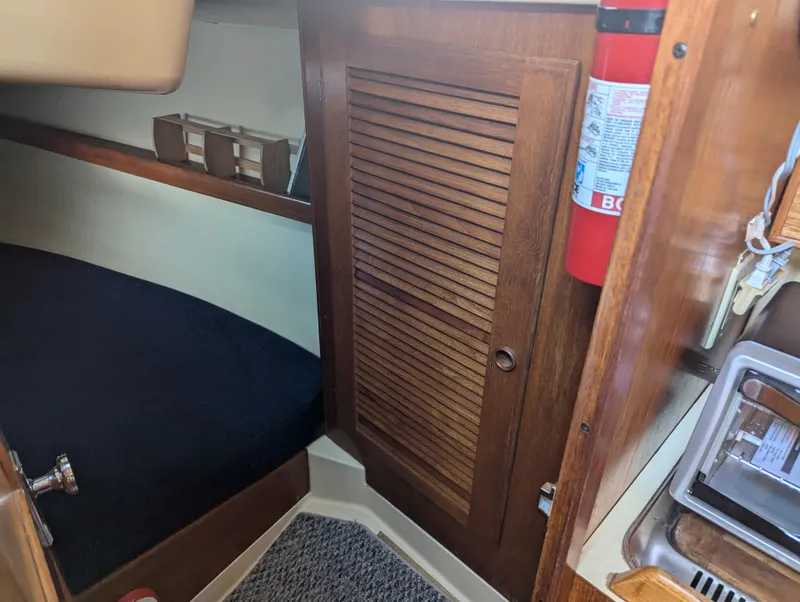 Slide: The Image of 1985 Pearson P-28 cabin interior with wooden cabinetry and fire extinguisher. - 21