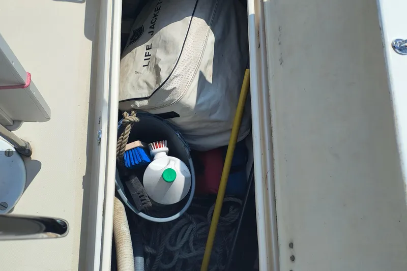 Slide: The Image of Storage compartment on a 1985 Pearson P-28 sailboat with life jacket and cleaning supplies. - 36