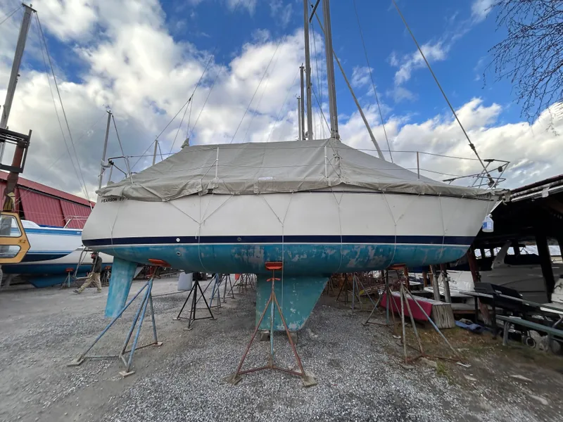 Slide: The Image of 1985 Pearson P-28 sailboat on stands, covered, with cloudy sky background. - 4