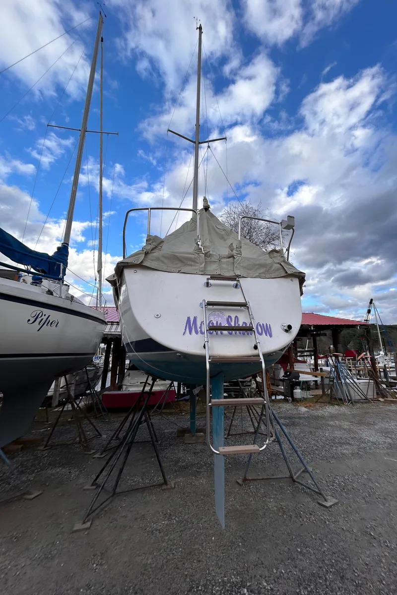 Slide: The Image of 1985 Pearson P-28 sailboat on stands under a cloudy sky. - 7