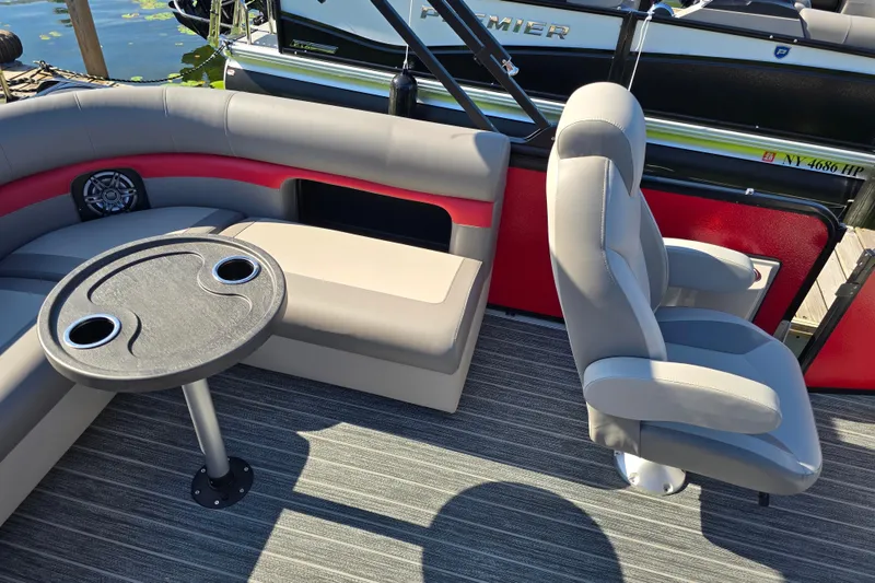 Slide: The Image of 2025 Premier 210 SunSation RE boat interior with seating and table, docked by water. - 12