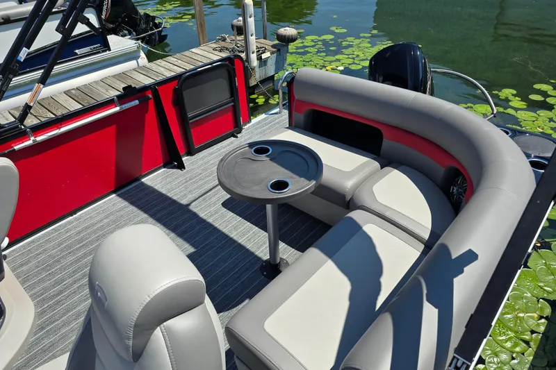 Slide: The Image of 2025 Premier 210 SunSation RE pontoon boat with stylish seating and table on calm water. - 15