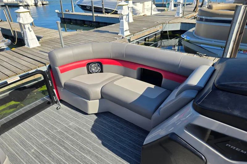 Slide: The Image of 2025 Premier 210 SunSation RE pontoon boat with stylish seating at a marina. - 16