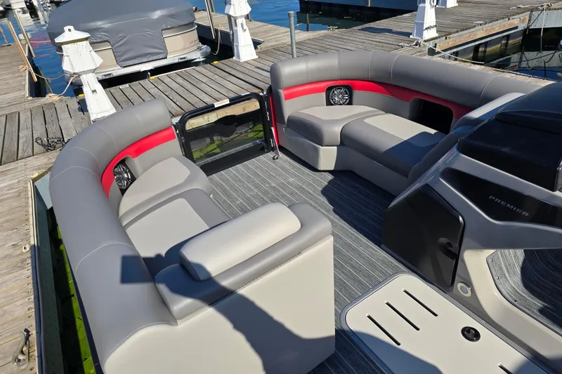 Slide: The Image of 2025 Premier 210 SunSation RE pontoon boat interior with gray and red seating at dock. - 18
