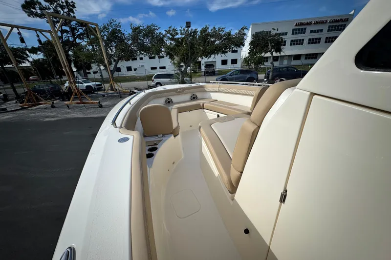 Slide: The Image of 2026 Scout 260 LXF boat interior with beige seating and cup holders, parked outdoors. - 18