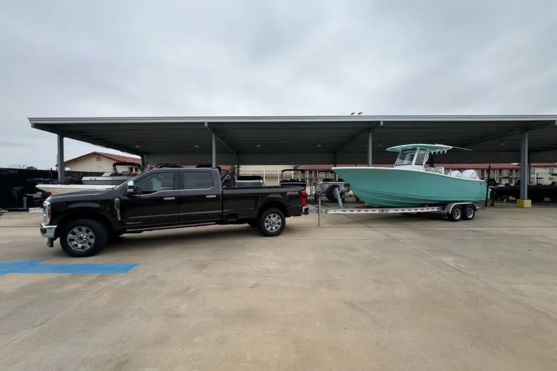 Slide: The Image of 2024 Sportsman Open 252 Center Console boat on trailer, towed by a black pickup truck. - 5