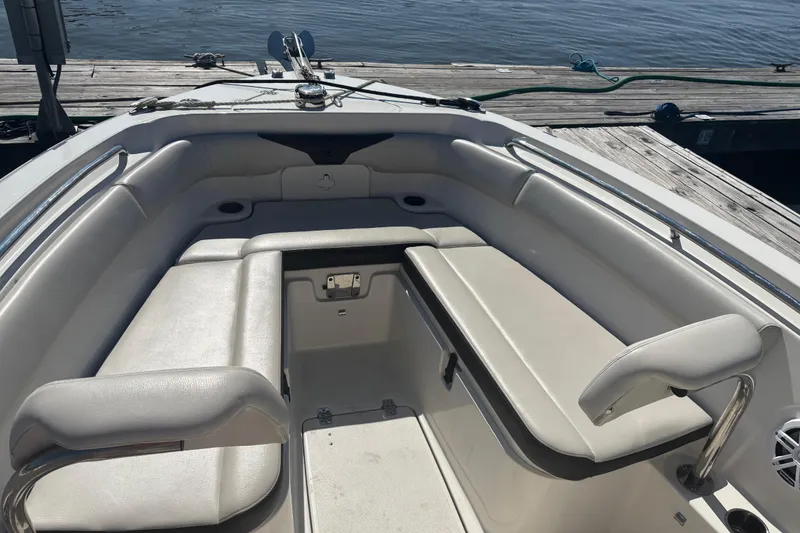 Slide: The Image of 2024 Sailfish 241 CC boat interior with cushioned seating, docked by the water. - 11