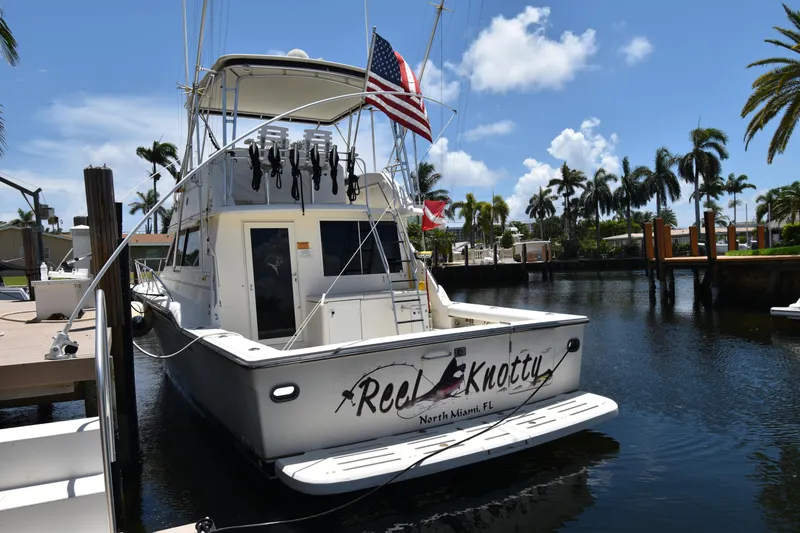 The Image of 1997 Tiara 4300 yacht docked in sunny marina with palm trees and flags. - 1