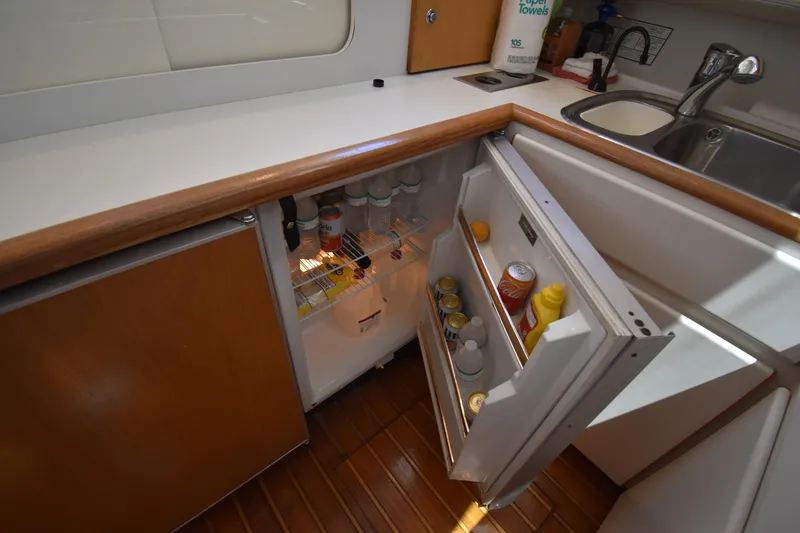 Slide: The Image of 1997 Tiara 4300 yacht kitchen with open fridge, wooden cabinets, and sink. - 22