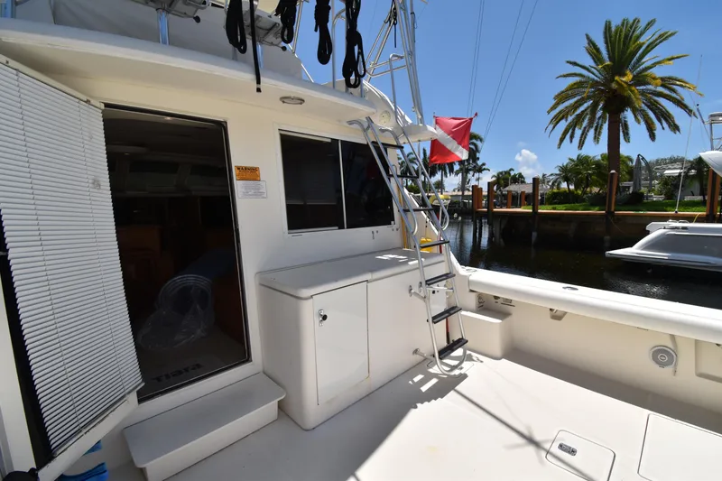 Slide: The Image of 1997 Tiara 4300 yacht deck with ladder, docked near palm trees and waterway. - 28