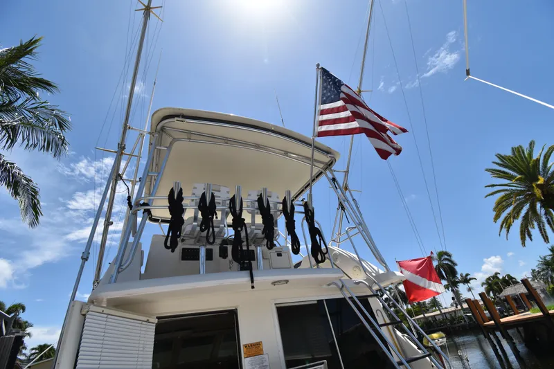 Slide: The Image of 1997 Tiara 4300 yacht with American flag, docked under sunny skies and palm trees. - 4