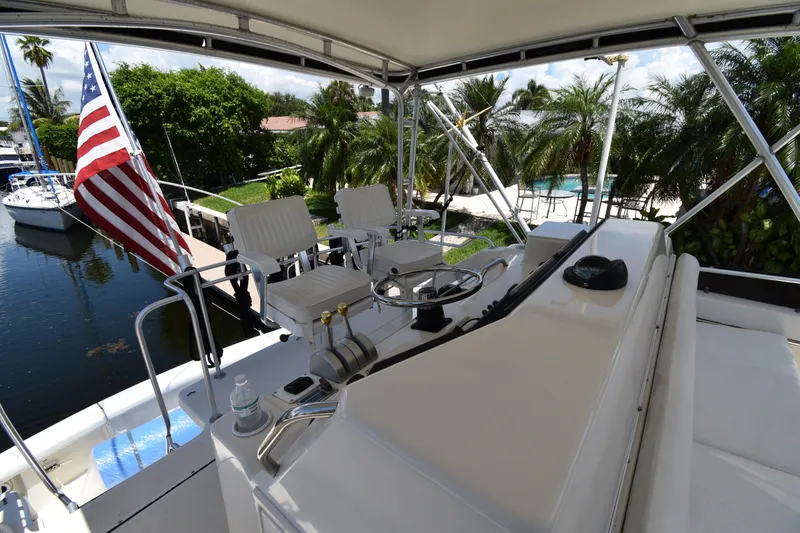 Slide: The Image of 1997 Tiara 4300 yacht helm with American flag, docked near lush greenery. - 9