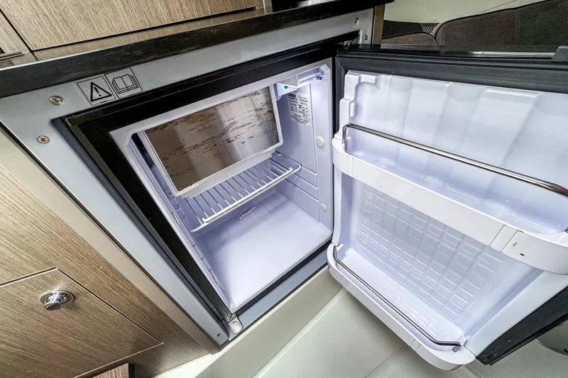 Slide: The Image of 2022 Beneteau America Flyer 8 Sundeck interior fridge, open with shelving and storage. - 13