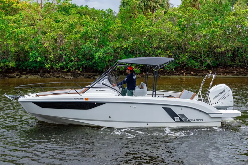 Slide: The Image of 2022 Beneteau America Flyer 8 Sundeck boat cruising on a river with lush greenery. - 7