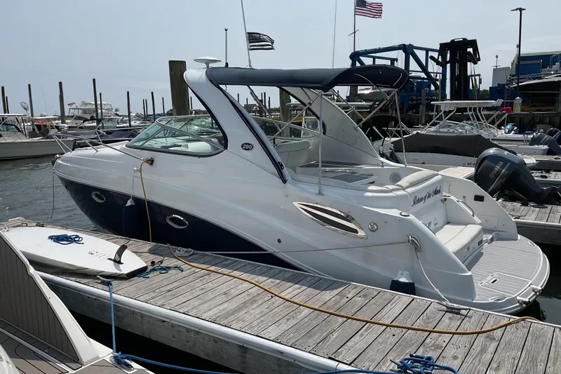 The Image of 2013 Rinker 290 Express Cruiser docked at marina, featuring sleek design and blue accents. - 0