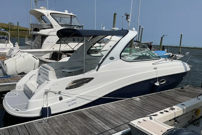 Slide: The Image of 2013 Rinker 290 Express Cruiser docked at marina, featuring sleek design and blue accents. - 1