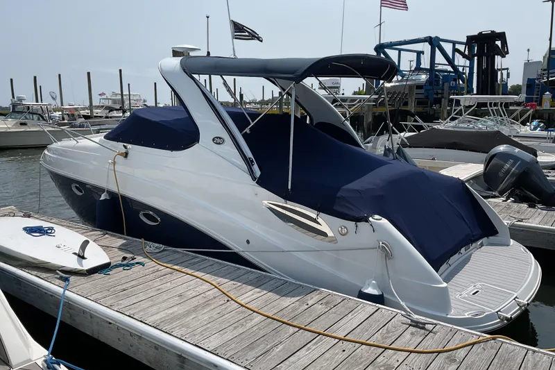 Slide: The Image of 2013 Rinker 290 Express Cruiser docked at a marina with blue cover. - 11